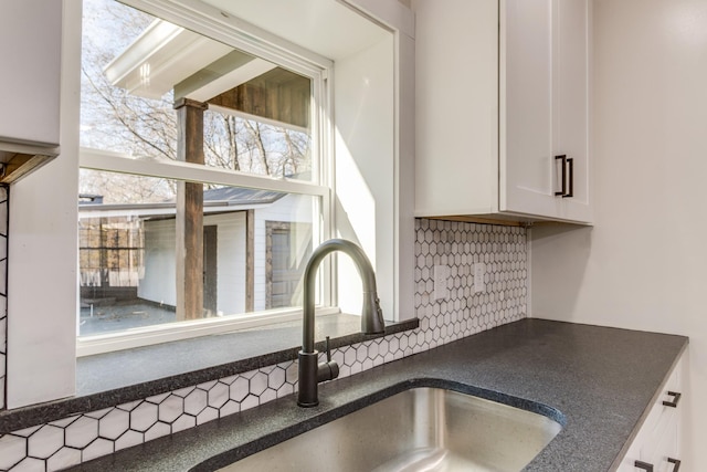 details with sink, white cabinetry, and backsplash