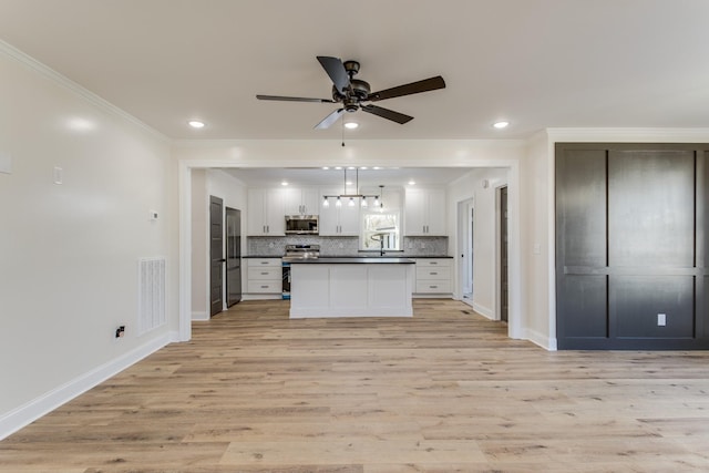 kitchen with white cabinetry, ornamental molding, appliances with stainless steel finishes, and light hardwood / wood-style flooring