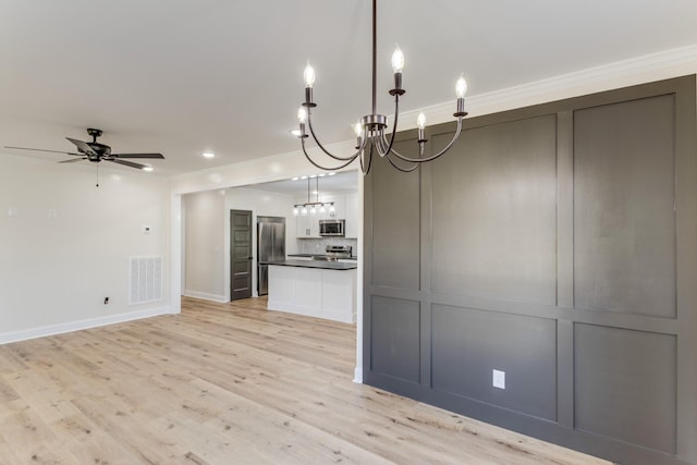 interior space with light wood-type flooring, ceiling fan with notable chandelier, stainless steel appliances, decorative light fixtures, and white cabinetry