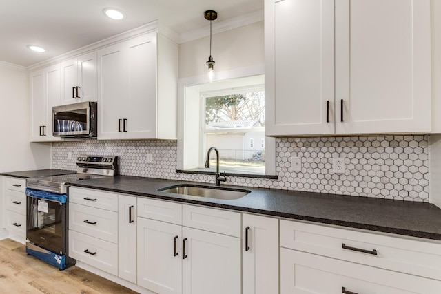 kitchen with sink, ornamental molding, light hardwood / wood-style floors, white cabinetry, and stainless steel appliances