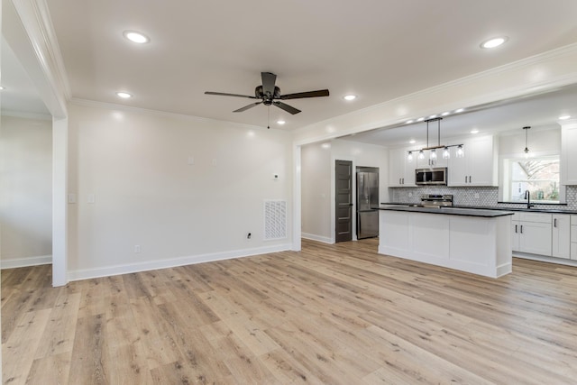 kitchen with appliances with stainless steel finishes, ornamental molding, light hardwood / wood-style floors, white cabinetry, and hanging light fixtures