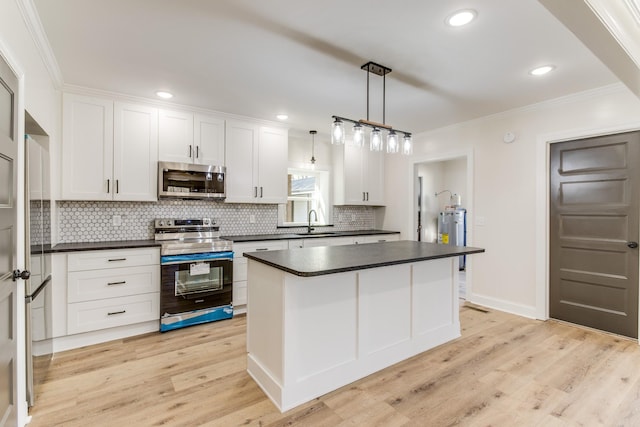 kitchen featuring white cabinets, appliances with stainless steel finishes, a kitchen island, and pendant lighting