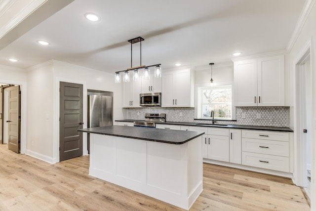 kitchen with white cabinetry, sink, hanging light fixtures, a kitchen island, and appliances with stainless steel finishes