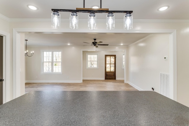 entrance foyer featuring ceiling fan with notable chandelier, light wood-type flooring, crown molding, and a wealth of natural light