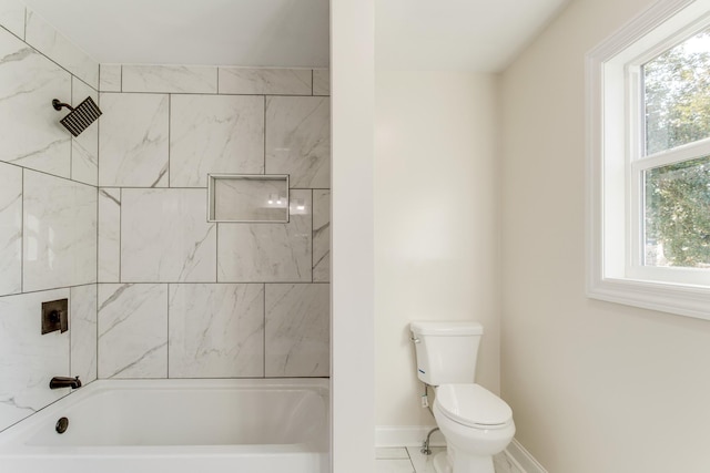 bathroom featuring tiled shower / bath, toilet, and plenty of natural light