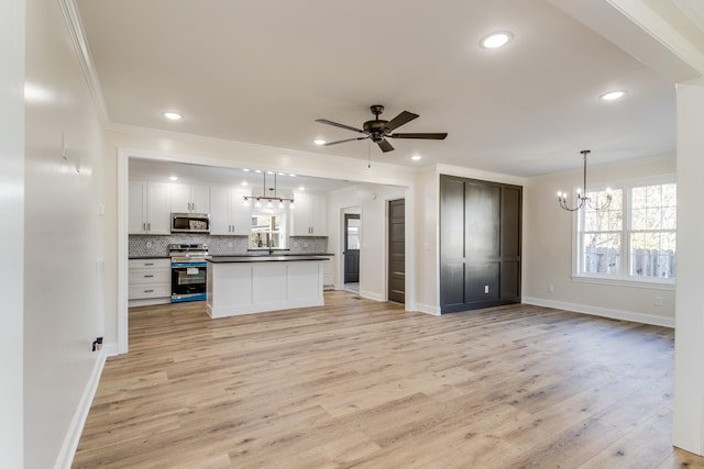 kitchen with white cabinets, appliances with stainless steel finishes, light wood-type flooring, and decorative light fixtures