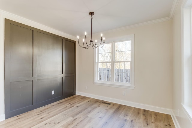 unfurnished dining area with a chandelier, light wood-type flooring, and ornamental molding