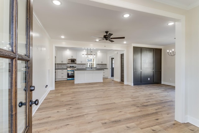 unfurnished living room with crown molding, light hardwood / wood-style flooring, and ceiling fan with notable chandelier