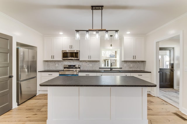 kitchen featuring white cabinetry, pendant lighting, stainless steel appliances, and light wood-type flooring