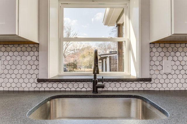 interior details with decorative backsplash, white cabinetry, and sink