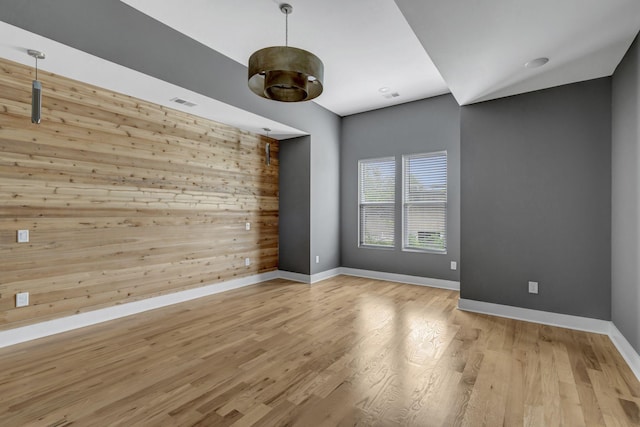 empty room with wood walls and light wood-type flooring