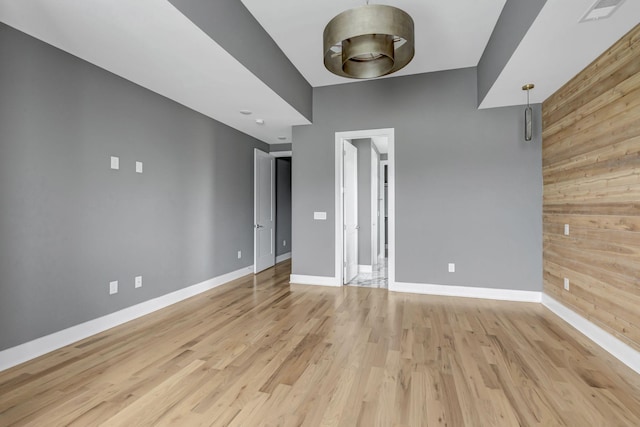 empty room featuring wooden walls and light hardwood / wood-style floors