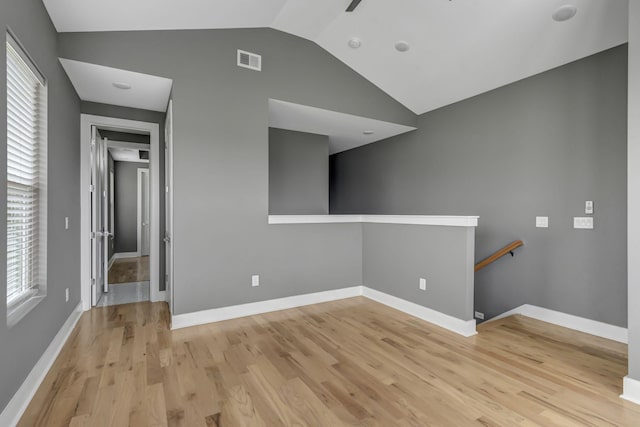 spare room with light hardwood / wood-style flooring, a wealth of natural light, and lofted ceiling