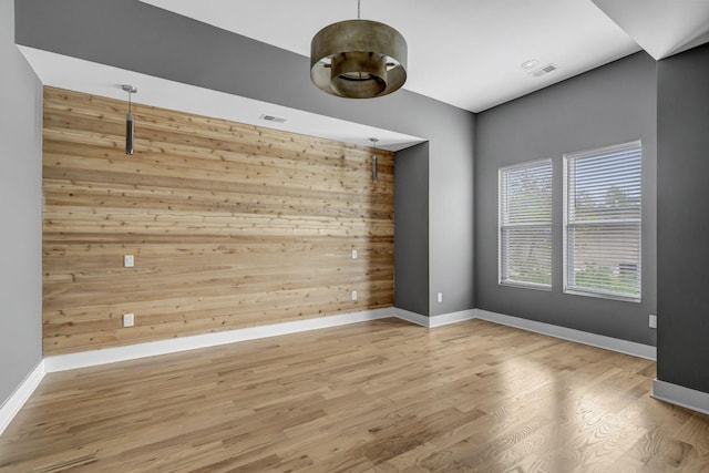 empty room featuring light wood-type flooring and wooden walls