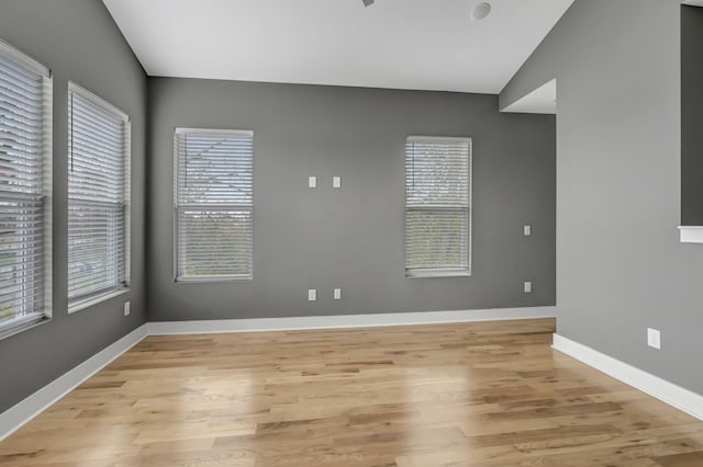 spare room with vaulted ceiling and light wood-type flooring