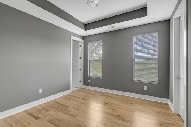 empty room with a tray ceiling and light wood-type flooring