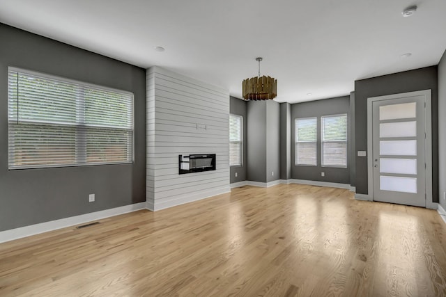 unfurnished living room featuring a large fireplace and light hardwood / wood-style flooring