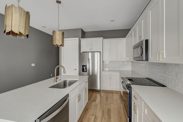 kitchen with backsplash, white cabinets, sink, decorative light fixtures, and stainless steel appliances