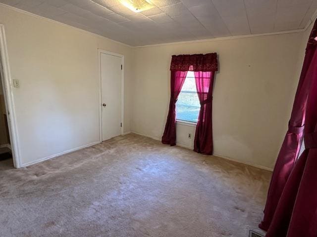 empty room featuring light colored carpet and ornamental molding