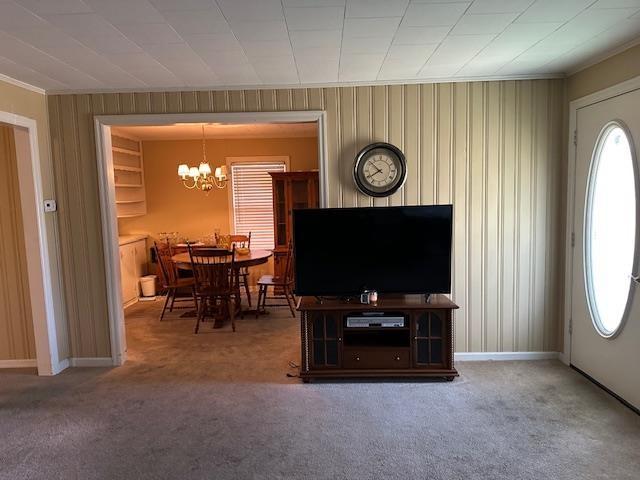 living room featuring carpet, an inviting chandelier, and crown molding