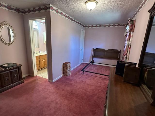 bedroom with carpet, a textured ceiling, and ensuite bathroom