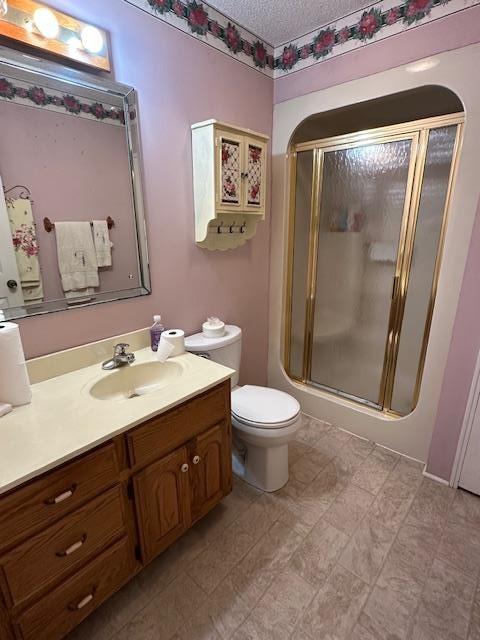 bathroom with vanity, an enclosed shower, a textured ceiling, and toilet