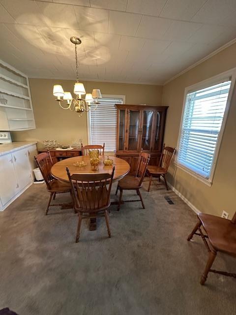 carpeted dining room featuring a notable chandelier and ornamental molding