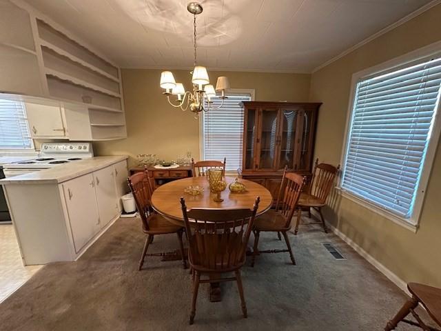 carpeted dining area featuring ornamental molding and a notable chandelier