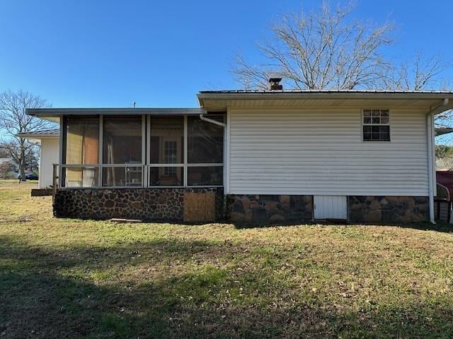 rear view of property featuring a sunroom and a yard