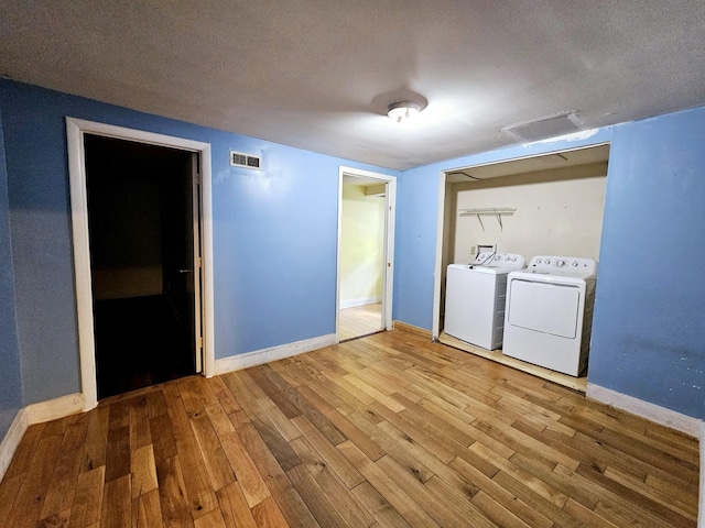 interior space with a closet, washer and clothes dryer, a textured ceiling, and hardwood / wood-style flooring