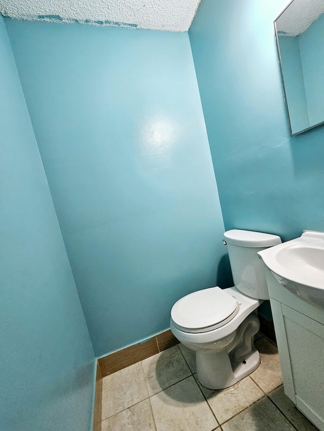 bathroom with tile patterned floors, vanity, a textured ceiling, and toilet