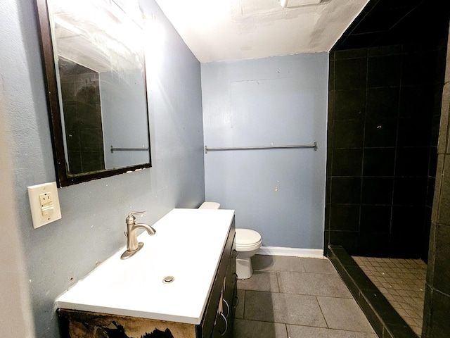 bathroom with tiled shower, vanity, tile patterned floors, and toilet