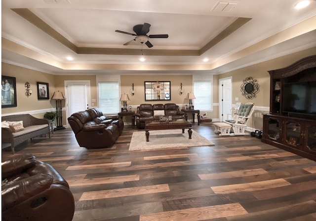 living room with a raised ceiling, plenty of natural light, and dark wood-type flooring