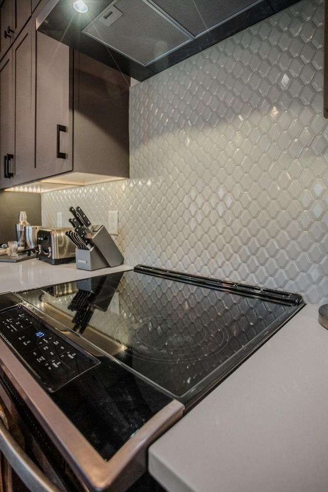 kitchen featuring black electric range, backsplash, and wall chimney exhaust hood