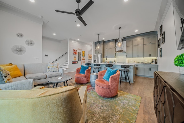 living room featuring ceiling fan, light hardwood / wood-style floors, and crown molding