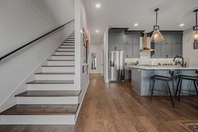 kitchen with a breakfast bar, dark hardwood / wood-style floors, stainless steel refrigerator with ice dispenser, and hanging light fixtures