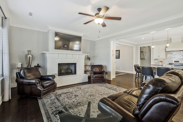 living room featuring a fireplace, ceiling fan, crown molding, and dark hardwood / wood-style floors