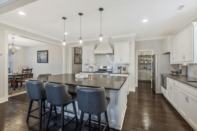 kitchen with hanging light fixtures, dark hardwood / wood-style floors, premium range hood, white cabinets, and appliances with stainless steel finishes