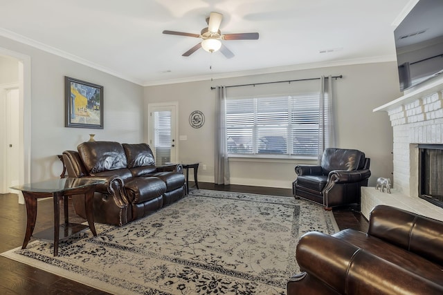 living room with hardwood / wood-style flooring, a brick fireplace, ceiling fan, and crown molding