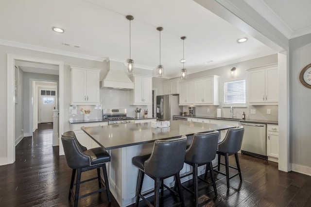 kitchen featuring pendant lighting, white cabinetry, premium range hood, and appliances with stainless steel finishes