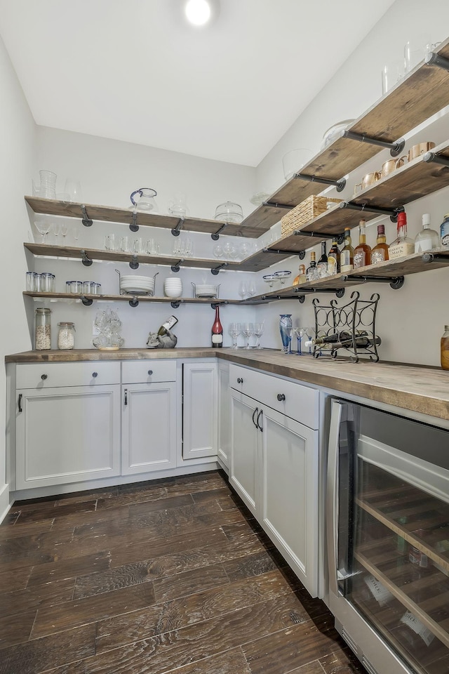 bar featuring dark hardwood / wood-style flooring, white cabinets, and beverage cooler