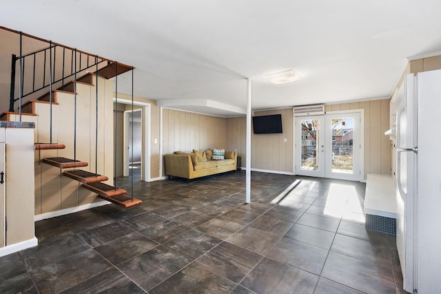 basement featuring wood walls, french doors, and white refrigerator