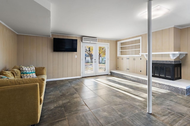 unfurnished living room featuring a wall mounted air conditioner, ornamental molding, wooden walls, and french doors