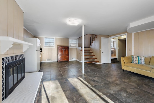 living room featuring wood walls and a tile fireplace