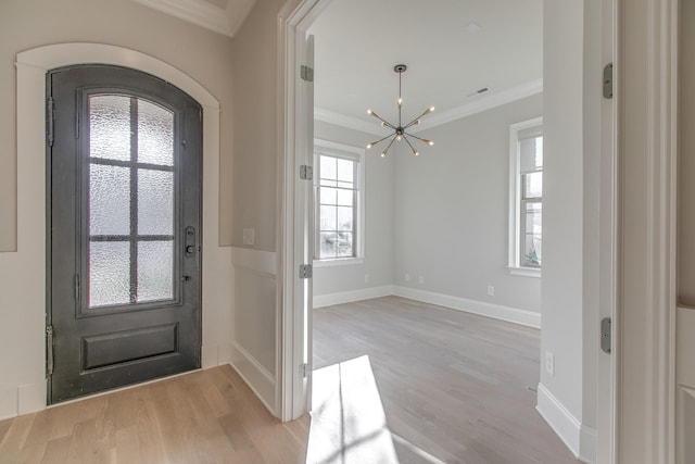 foyer featuring crown molding, a chandelier, and light hardwood / wood-style floors