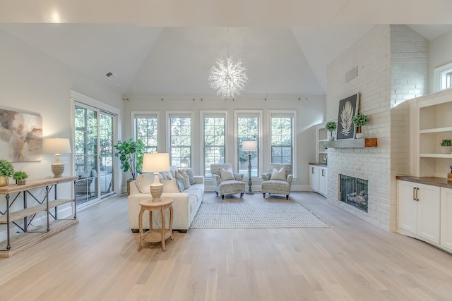 living room with a chandelier, high vaulted ceiling, a brick fireplace, and light wood-type flooring