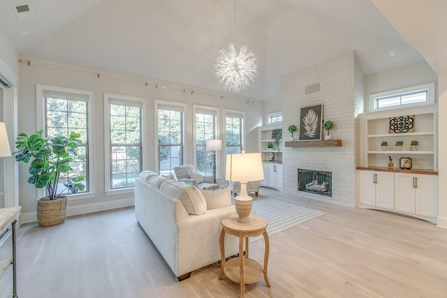 living room with built in shelves, a chandelier, high vaulted ceiling, light hardwood / wood-style flooring, and a fireplace