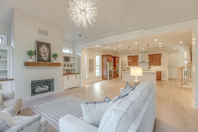 living room featuring built in shelves, ornamental molding, light hardwood / wood-style floors, and a brick fireplace