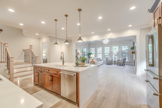 kitchen with pendant lighting, stainless steel appliances, sink, and a center island with sink