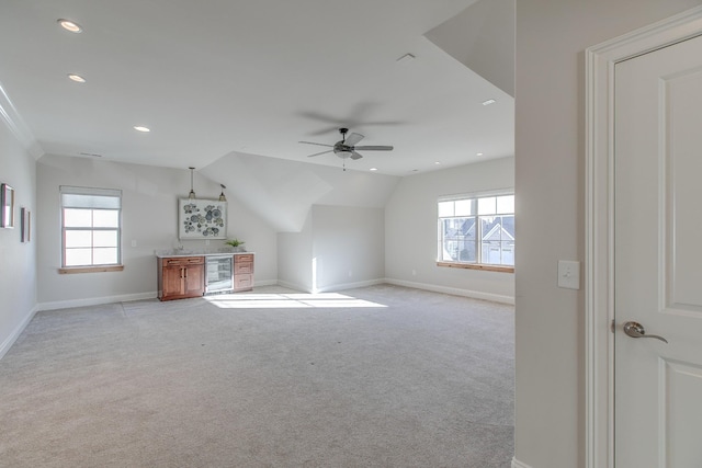 unfurnished living room with a healthy amount of sunlight, light colored carpet, beverage cooler, and ceiling fan